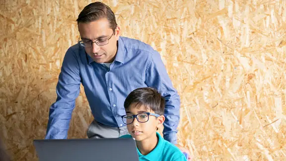 Programming instructor standing behind student with laptop