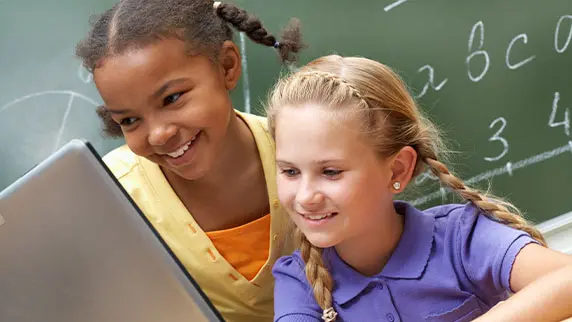 Picture of two children sitting behind a laptop smiling
