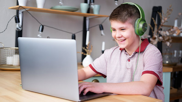 Happy child sitting behind a laptop smiling