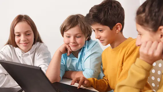 Group of students sitting behind a laptop smiling