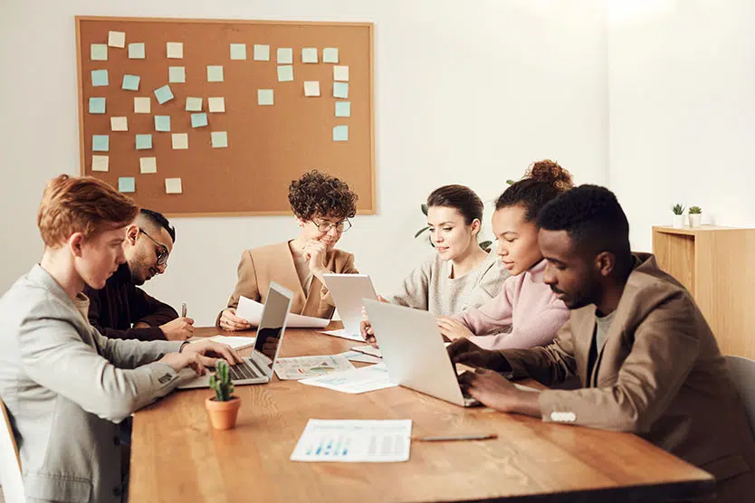 Group of people around a table with laptops, hard at work