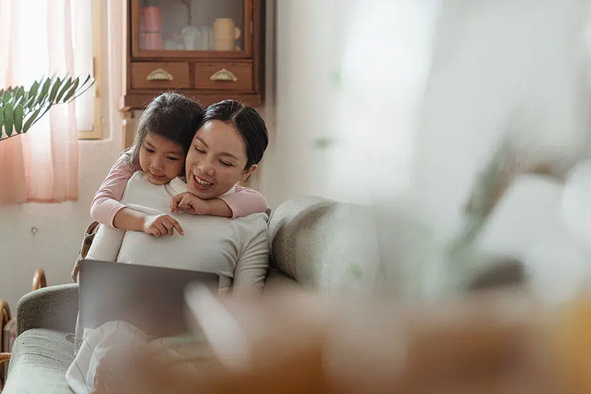 Daughter hugging mother in front of a computer