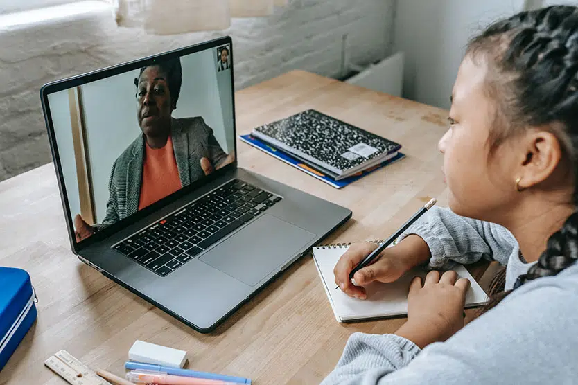 young girl looking at teacher on laptop