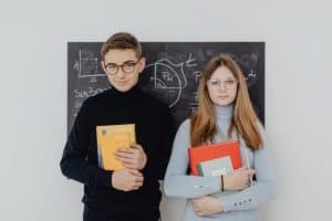 teenage guy and girl in front of a blackboard, looking sharp!