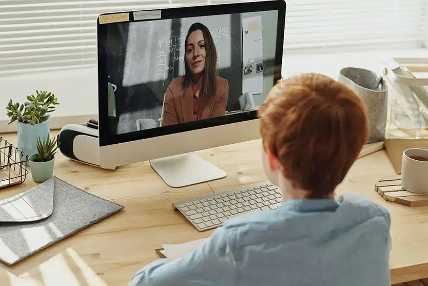 a boy looks at a woman on his computer screen