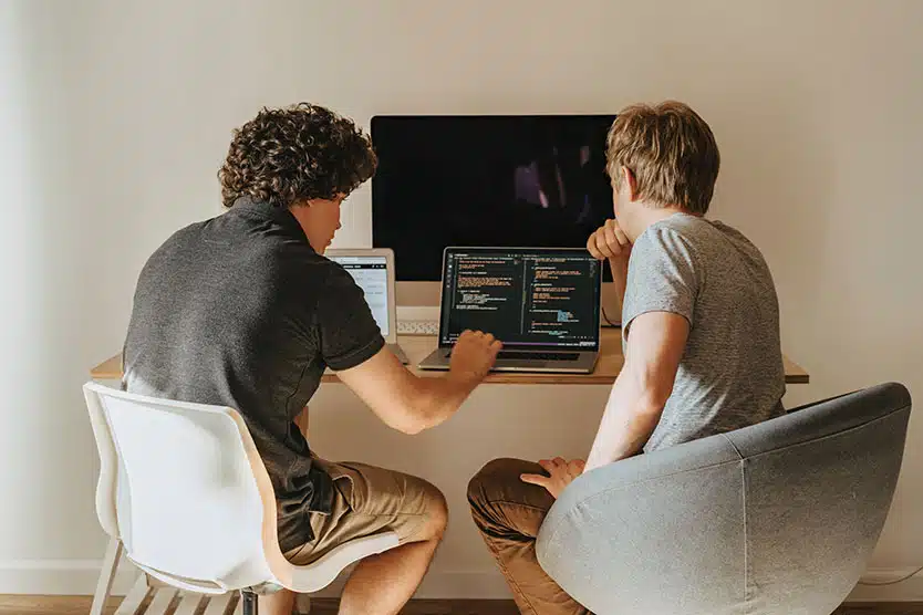 two young boys writing computer code beside each other