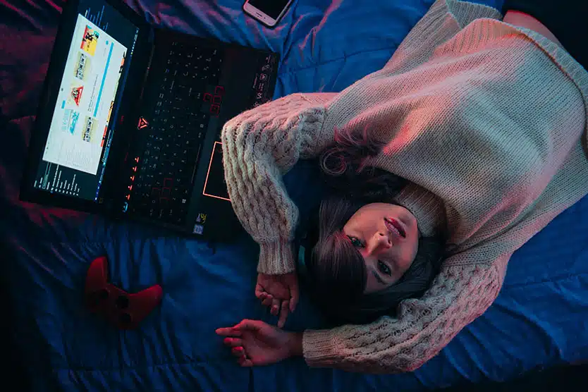 girl lying on a laptop on her bed