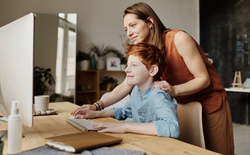 mother helping young boy at a desktop computer