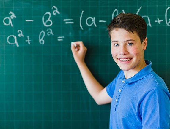 Boy writing on board smiling