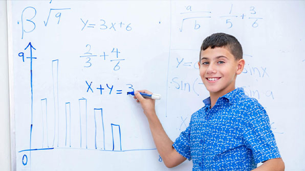 Portrait for school boy smiling and answering math question on the board