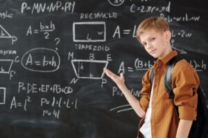 kid showing off math equations on a blackboard