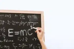 hand writing math equations in chalk, like E = mcsquared