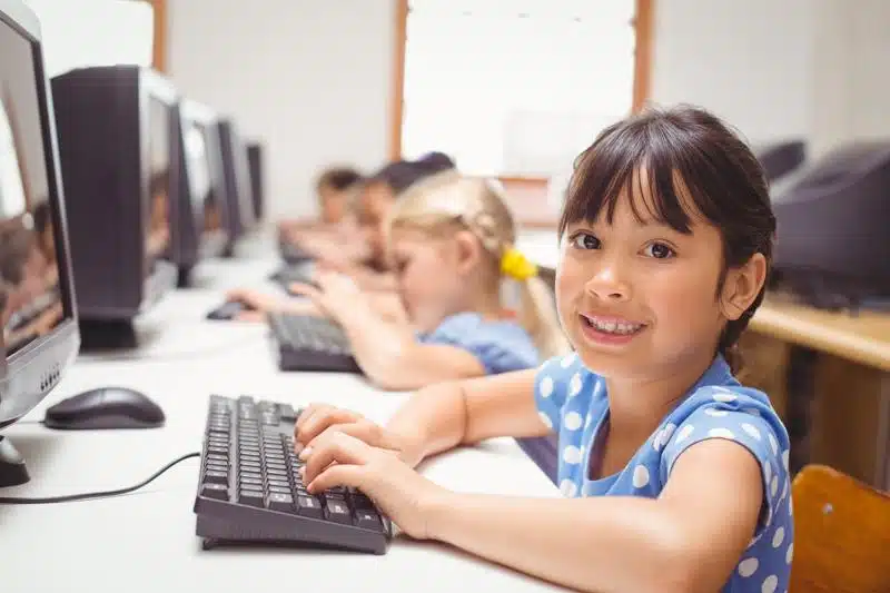 Children sitting at desk with computers